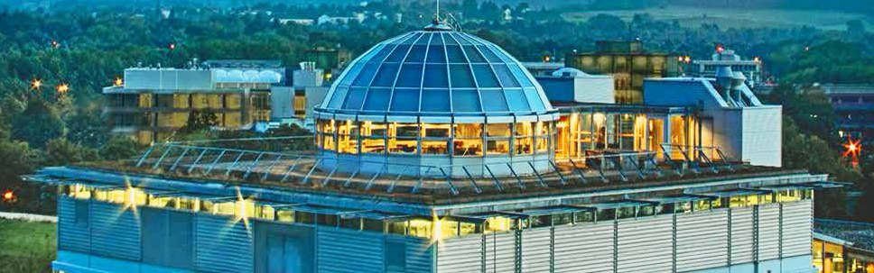 The AMICA building on Campus Melaten at dusk, with its illuminated glass dome on the roof.