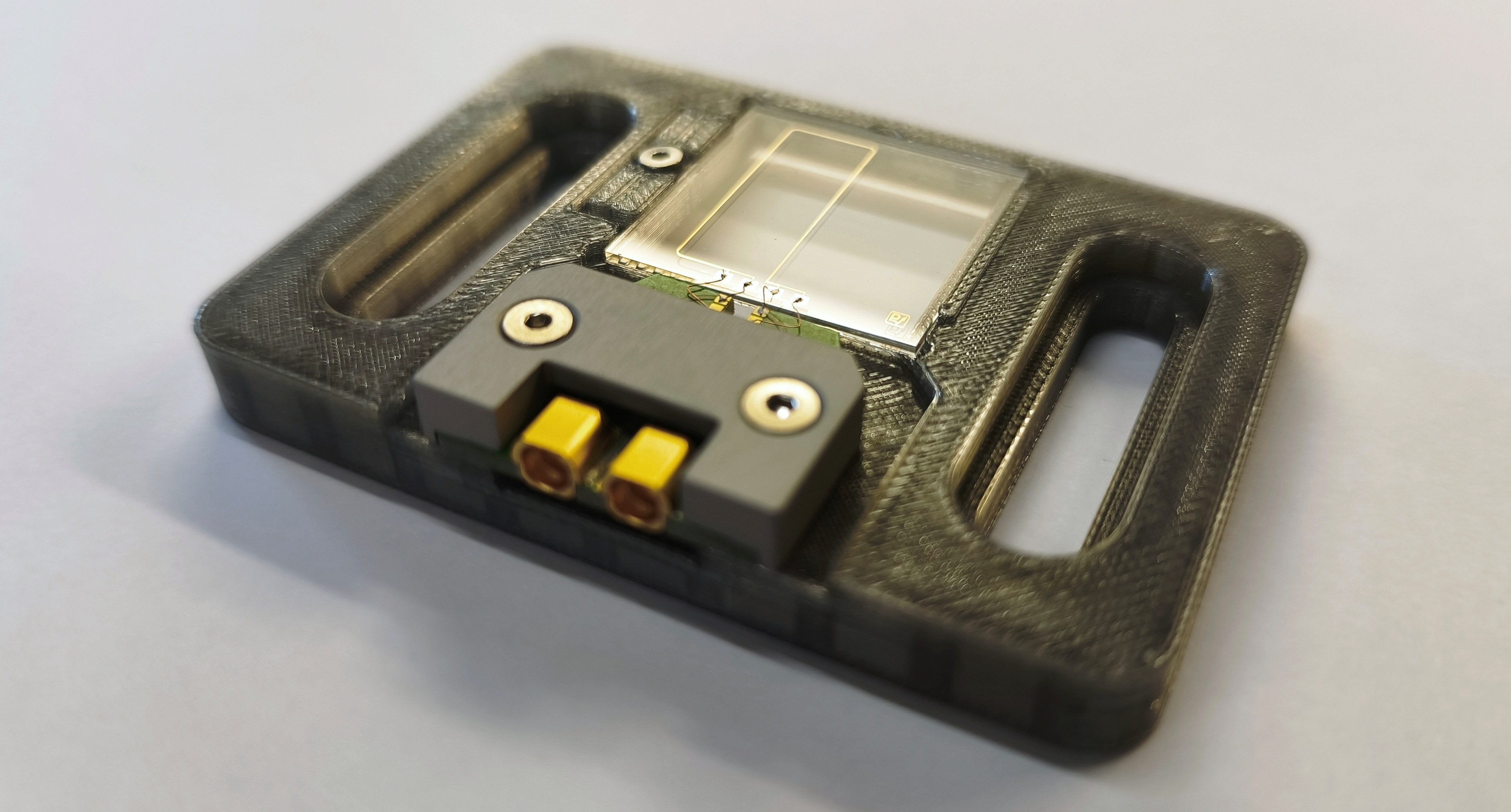 TeraLineX chip on a green carrier board with two gold SMP connectors, mounted on a translucent holder.